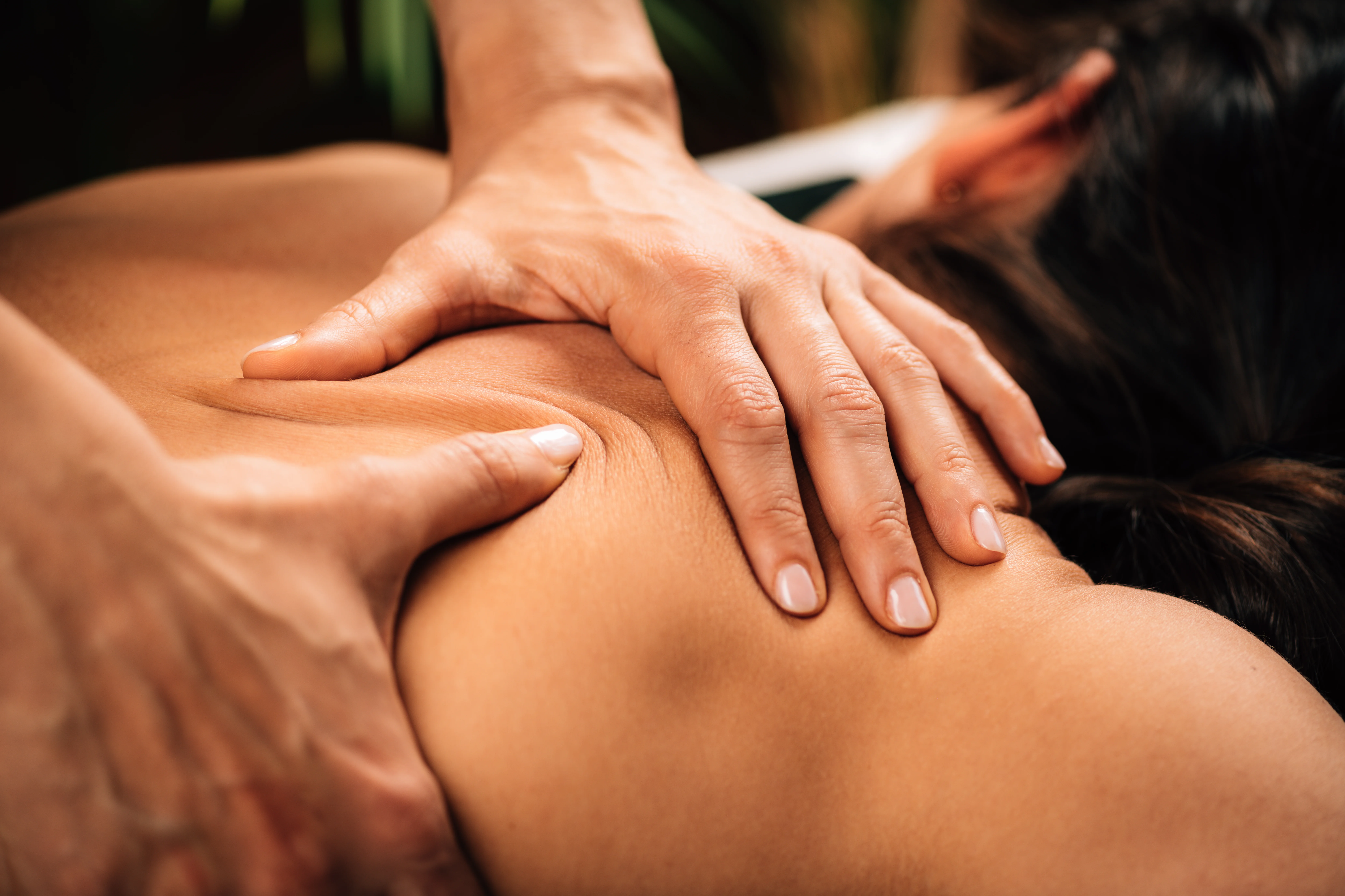 Registered massage therapist alleviating chronic back pain with close-up massage