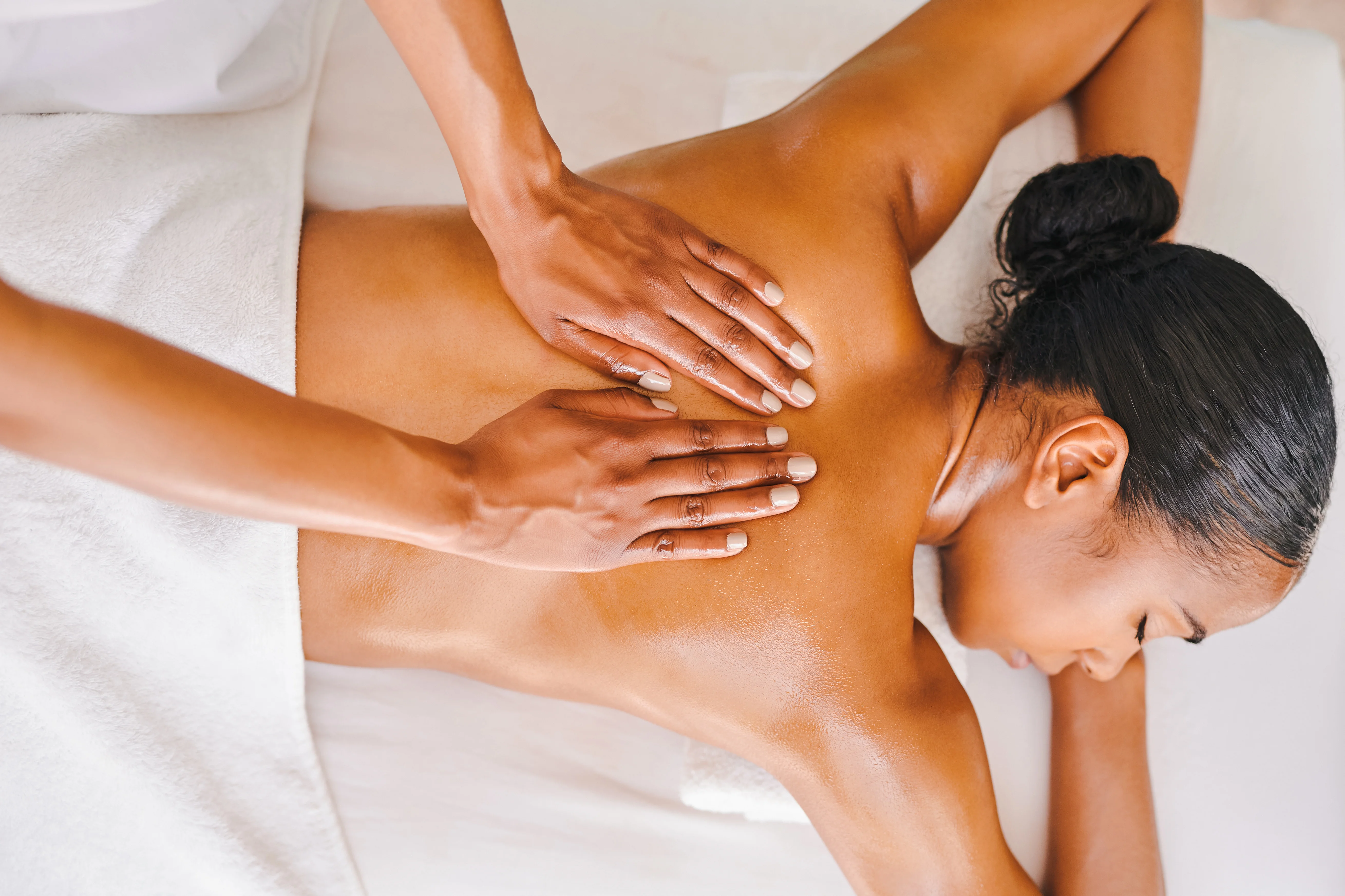 Close-up image of a massage therapist's hands massaging a woman's back, highlighting relief from chronic pain.