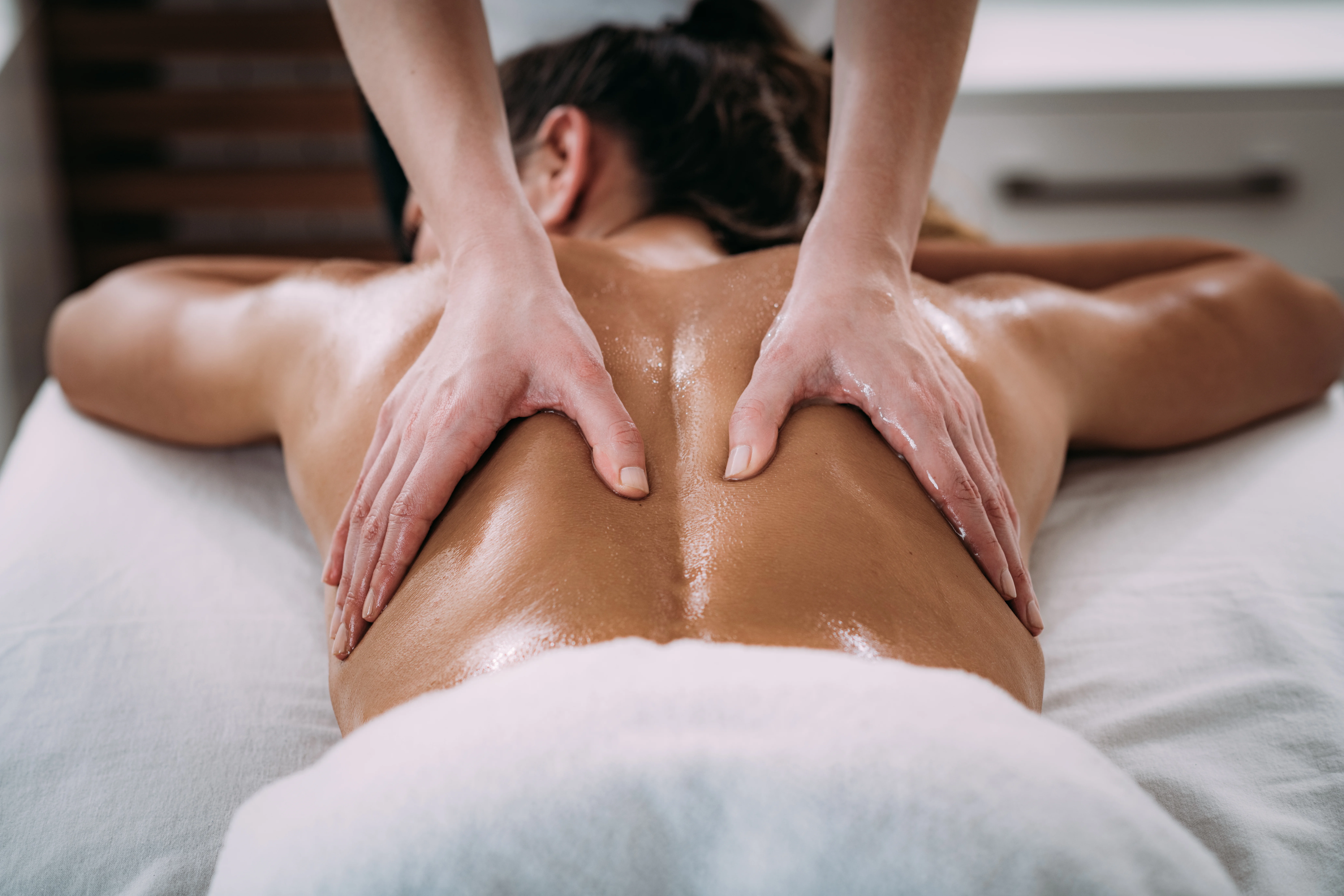 Close up of massage therapist providing therapeutic massage to a female back, illustrating the benefits beyond pain relief like stress reduction and improved sleep.
