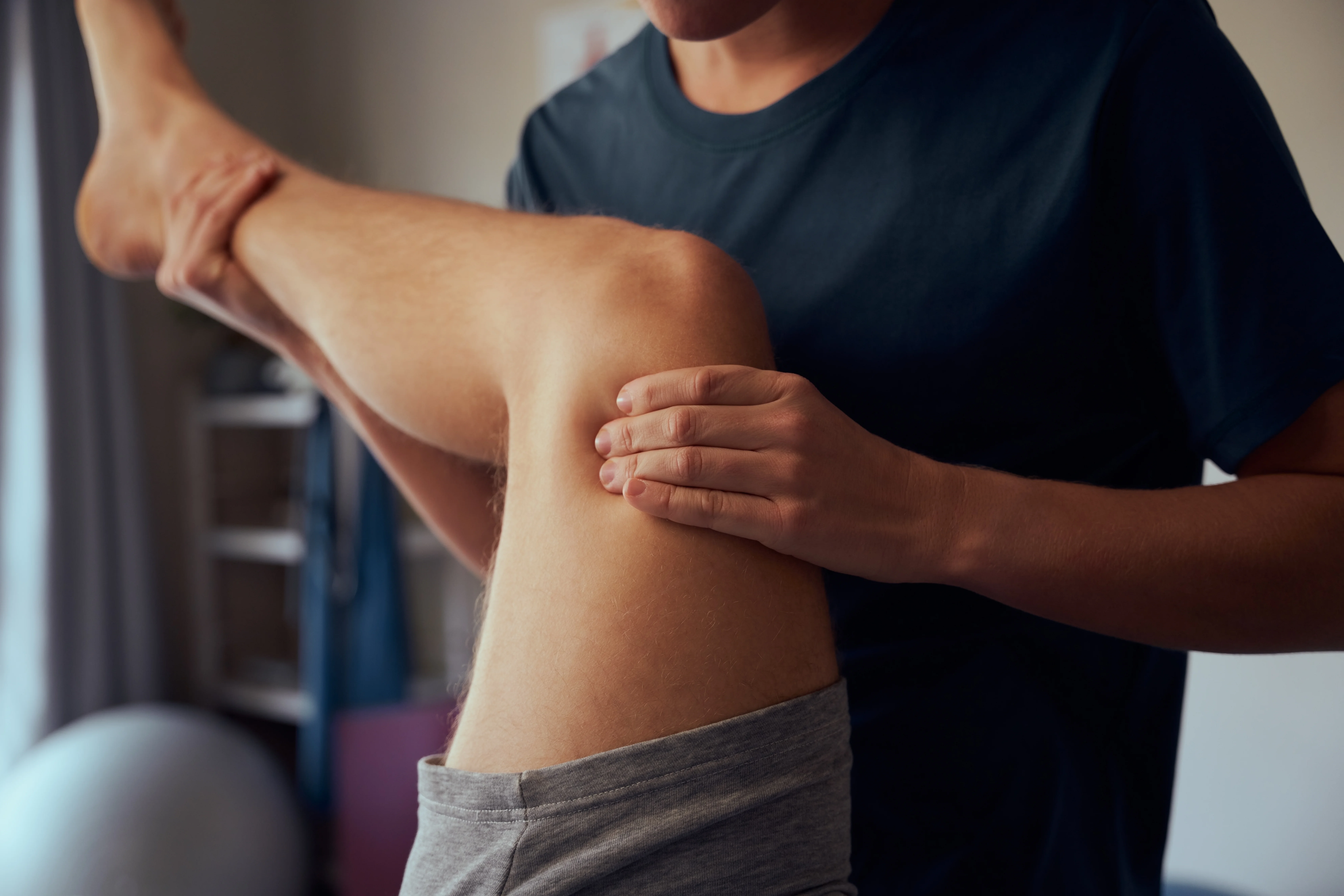 Close-up landscape photo of a registered massage therapist (RMT) working on the leg muscles of an athlete in Vancouver, focusing on soft tissue manipulation for sports injury recovery.